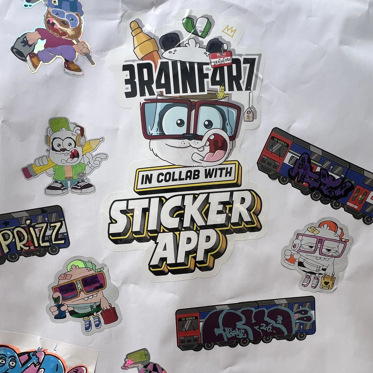 Wall covered in hand-coloured Brainfart x StickerApp die-cut stickers and S8 World train labels with graffiti tags