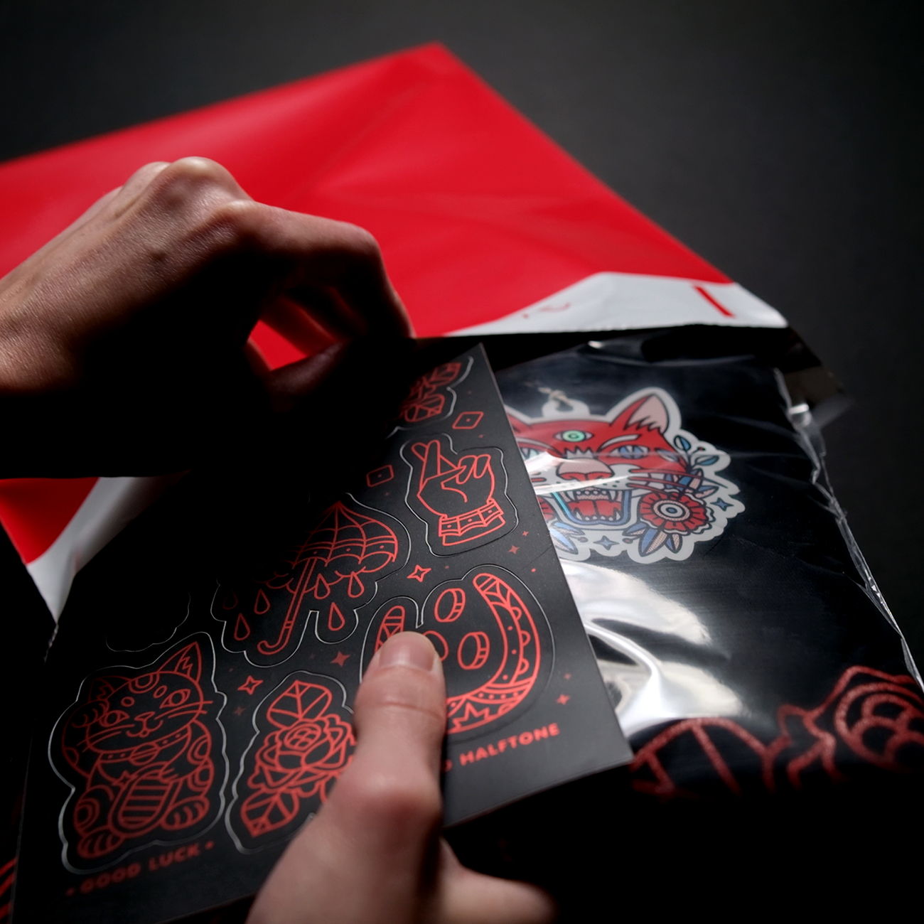 Hands including a custom matte mirror sticker sheet in a customer order as free merch.