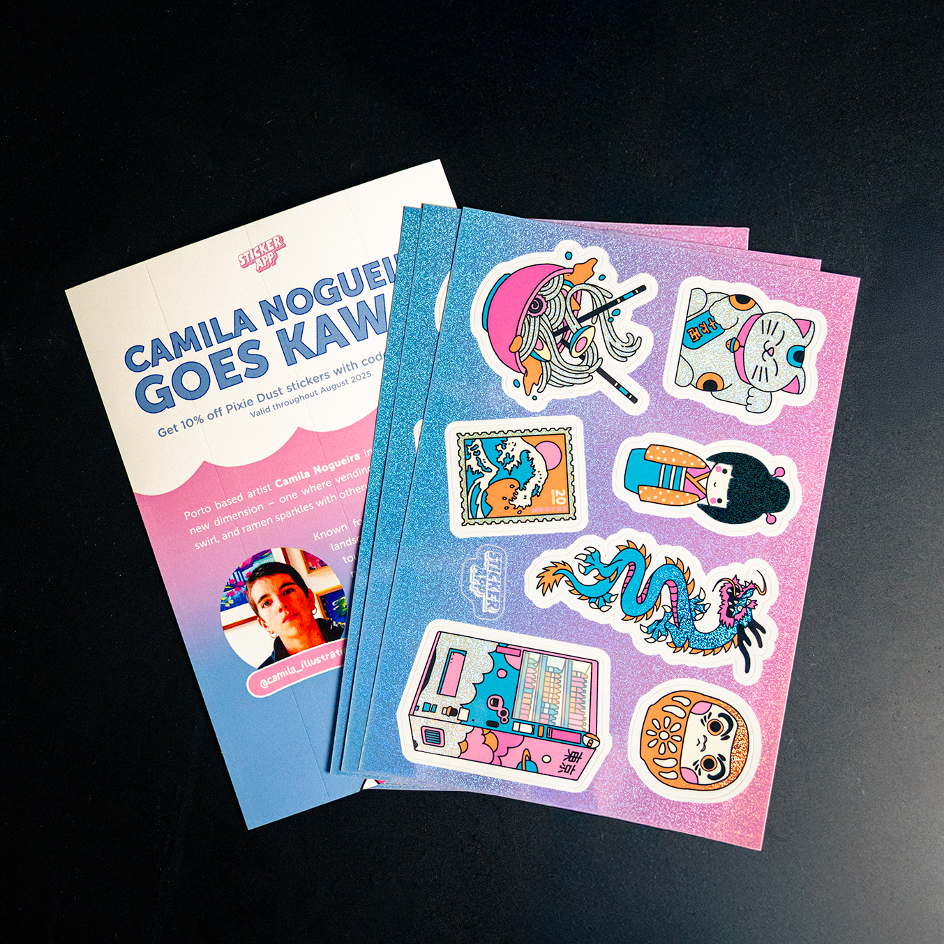 Stickers with colorful designs, including a dragon and a cat, next to a flyer with text about "Camila Nogueira Goes Kawaii."