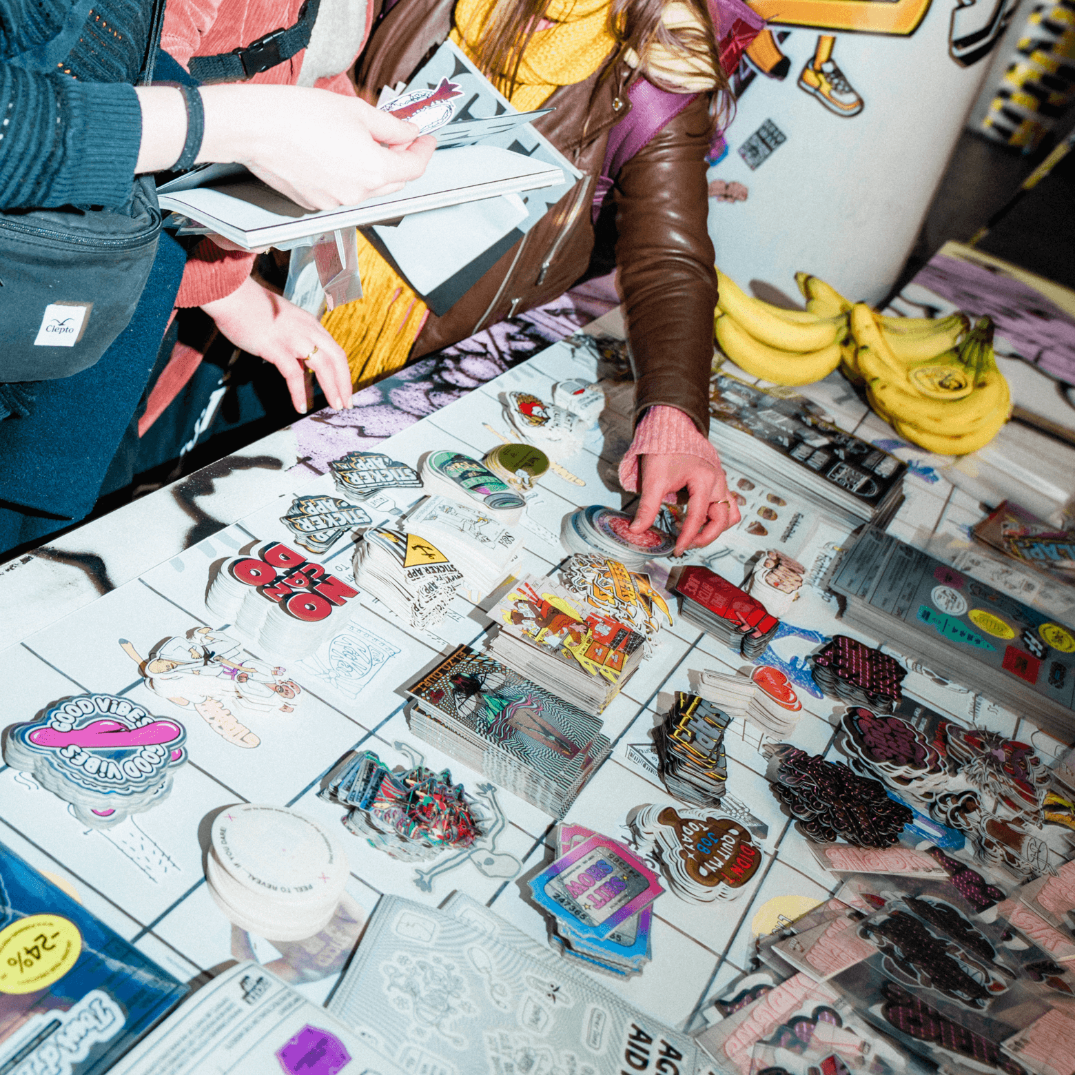 People browsing a table with colorful die cut stickers and sticker sheets.
