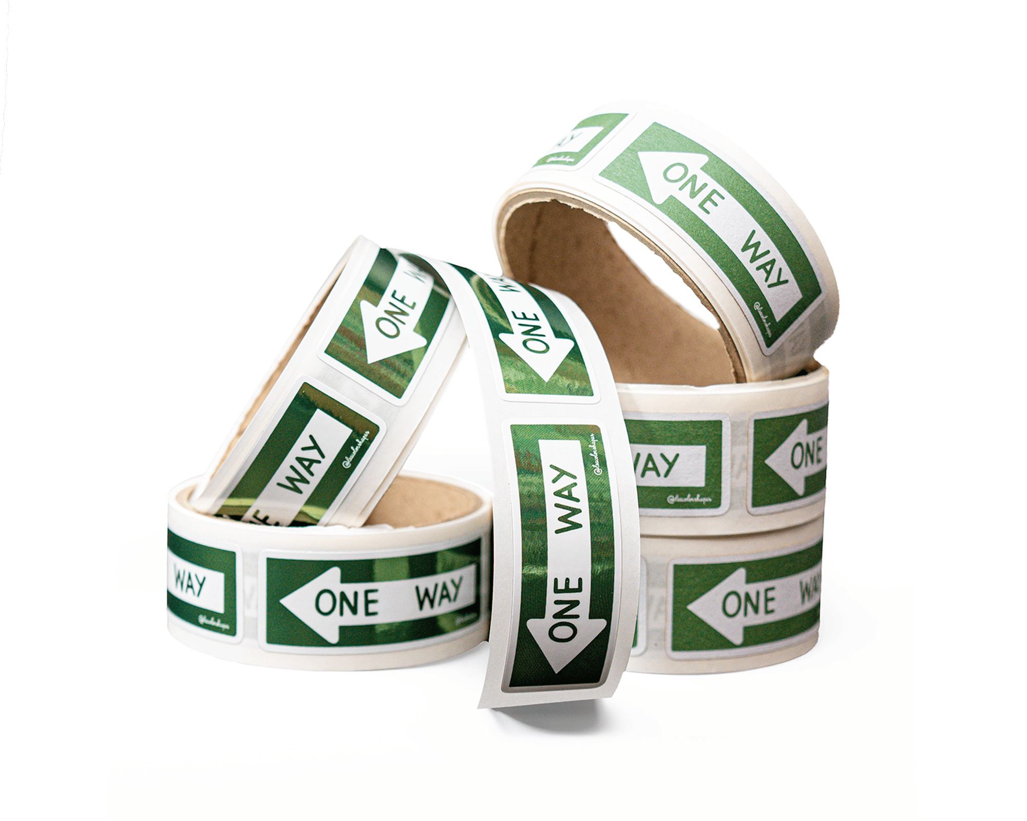 Rolls of labels with green "One Way" arrows stacked in a pile on a white background.