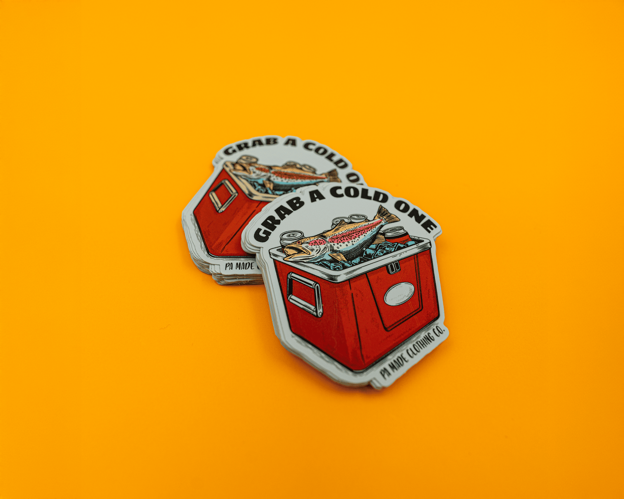 Vinyl stickers featuring a red cooler with fish and the text "Grab a Cold One" on an orange background.
