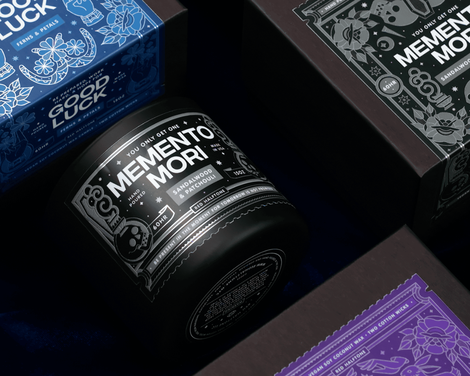 Black candle label "Memento Mori" surrounded by boxes with intricate designs, including a blue "Good Luck" box.