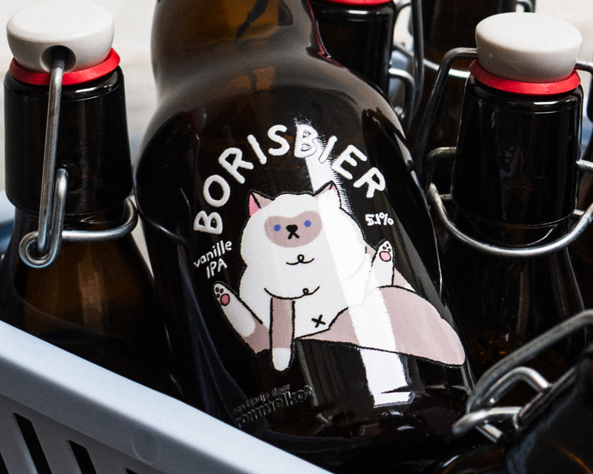 Brown beer bottle with a whimsical cat uv-transfer, text "BORISBIER Vanilla IPA 5%," in a blue crate.