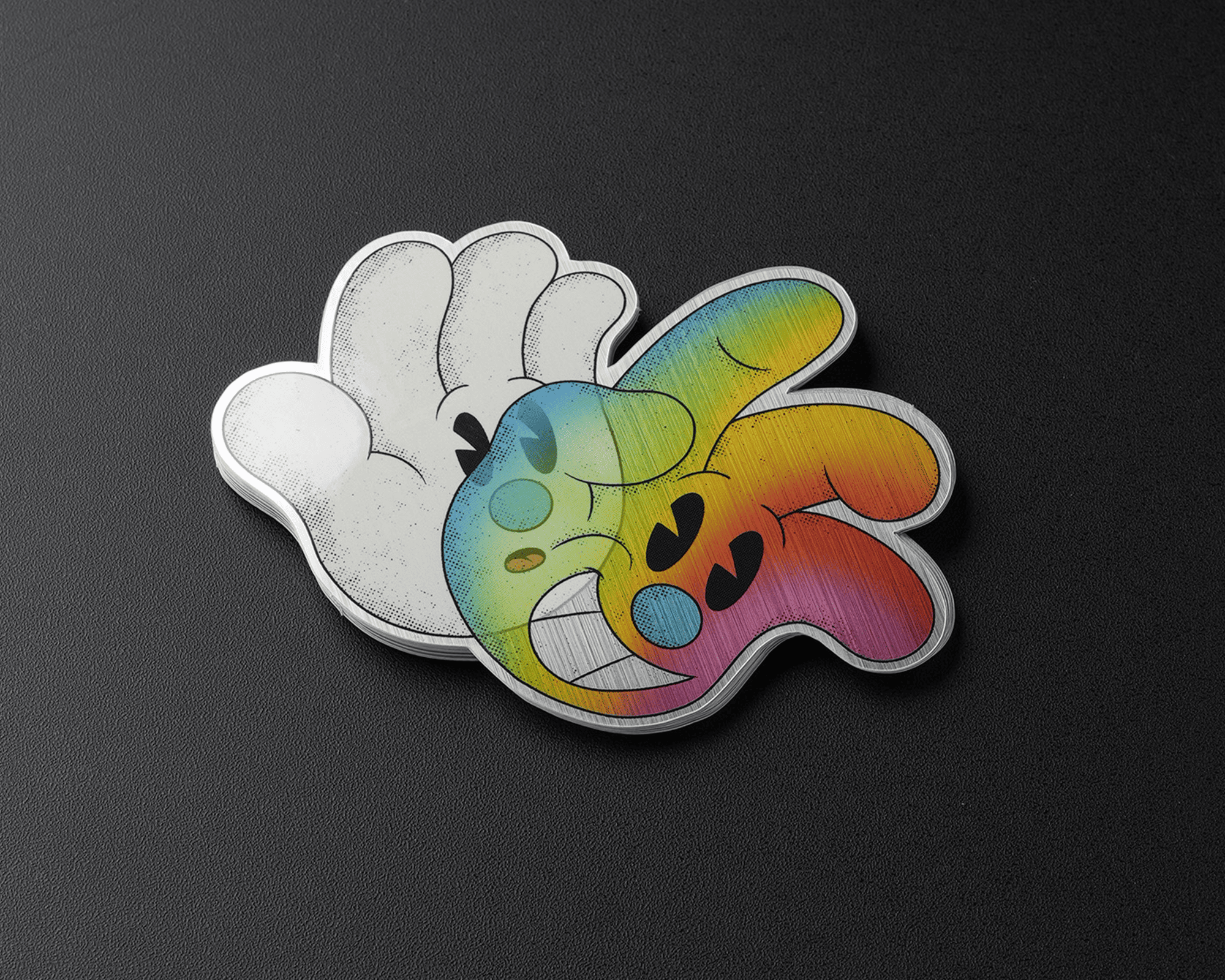 Two cartoon-style hand brushed aluminum stickers on a dark surface; one is white with black accents, the other is colorful with a rainbow gradient and facial features.