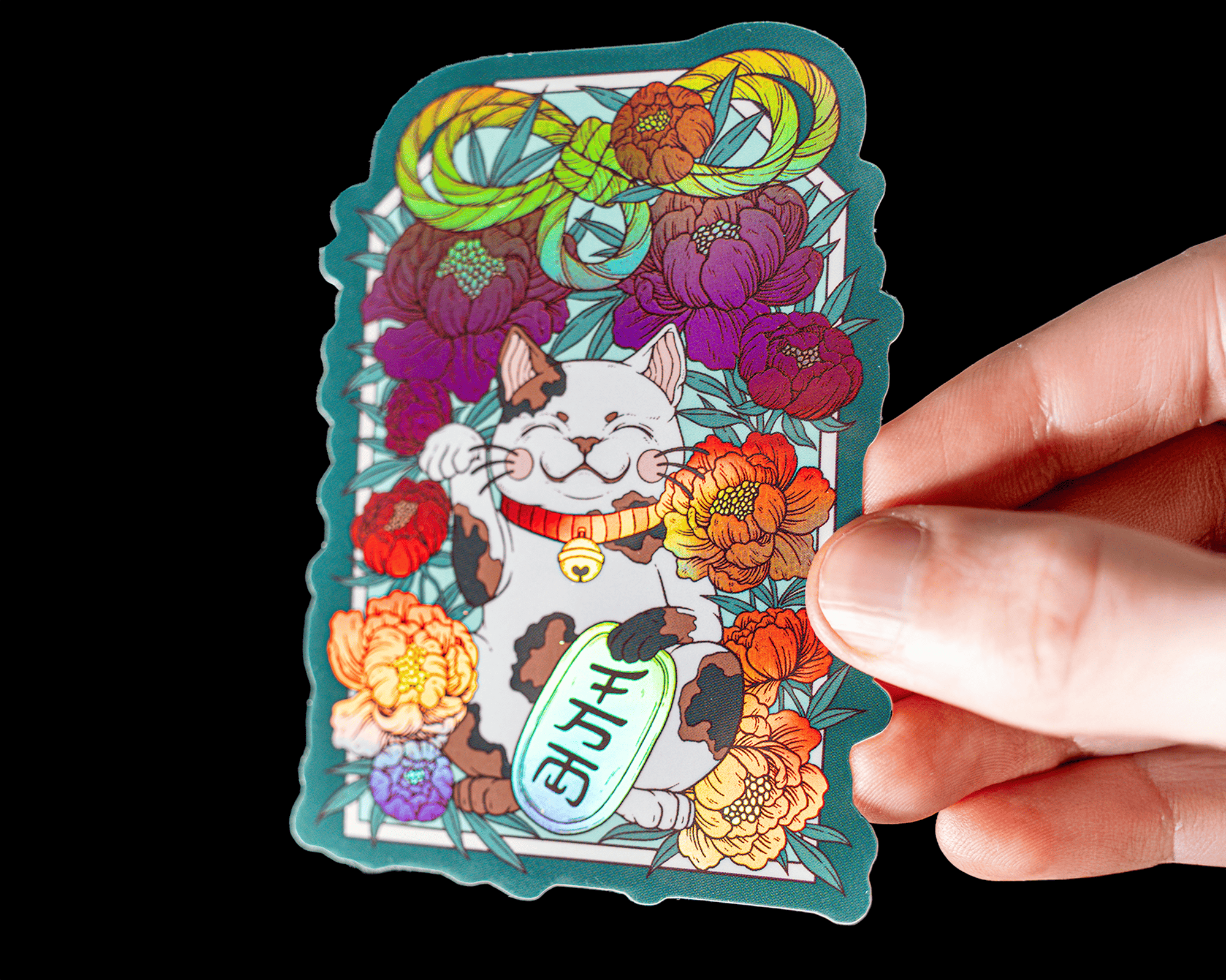 Hand holding a holographic sticker of a lucky cat surrounded by colorful flowers and leaves, with Japanese characters on the cat's coin.