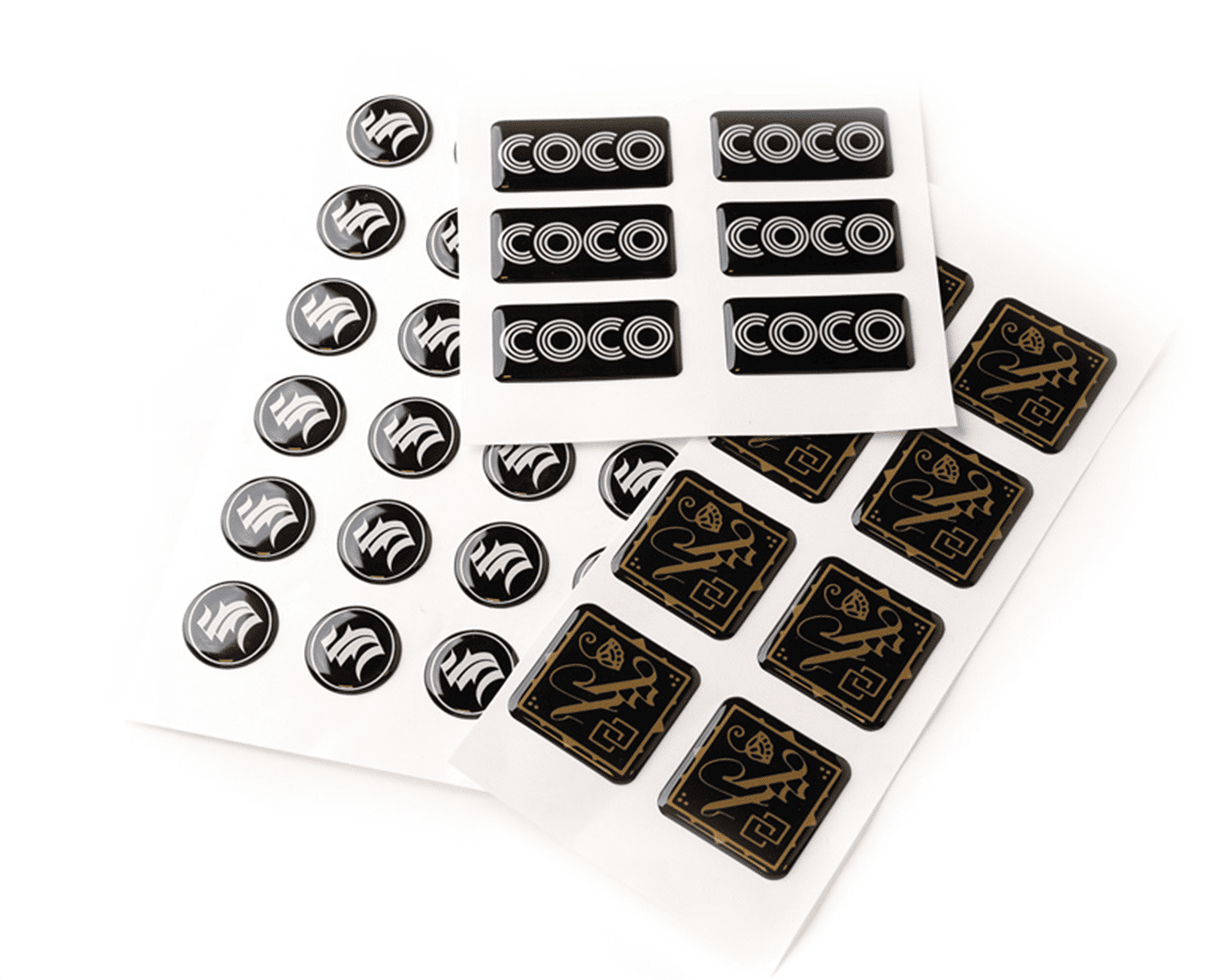 Sheets of black and gold epoxy stickers featuring various designs, including circular and rectangular shapes, arranged on a white background.