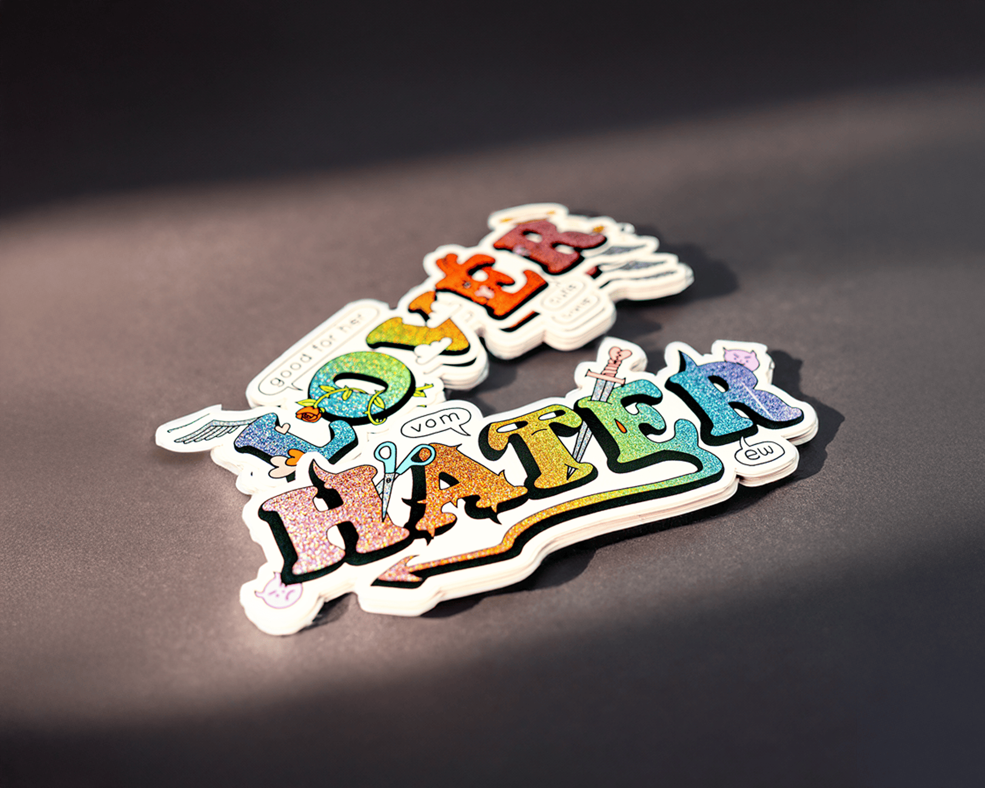 Colorful stickers with the words "lover" and "hater" in bold, stylized letters on a dark background.