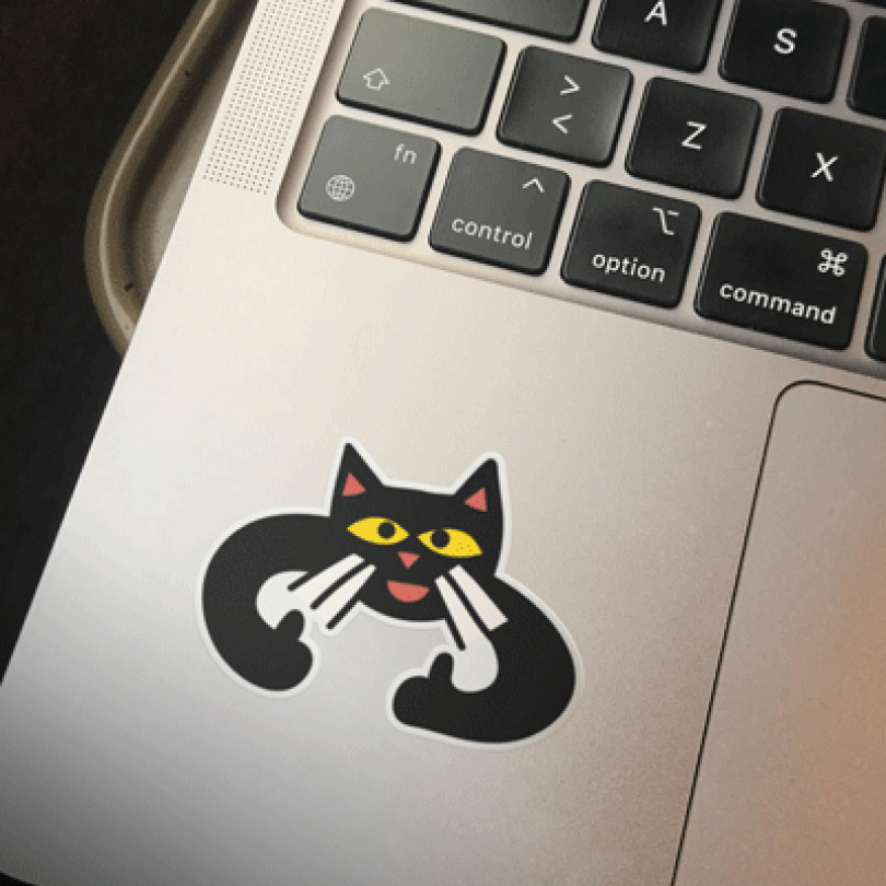A laptop computer with a sticker of a cat.